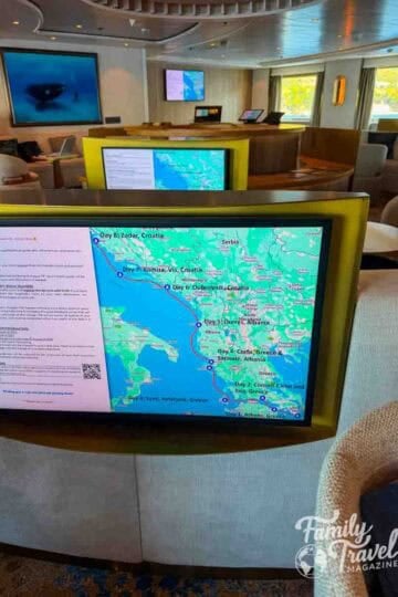 A digital screen displays a travel itinerary map with a red route line connecting various coastal locations.