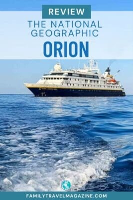 The National Geographic Orion with a dark blue hull and white superstructure anchored on the open ocean.