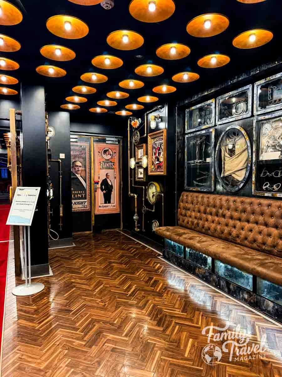 A room with a herringbone wood floor, a tufted leather bench, and a black ceiling featuring numerous circular light fixtures.