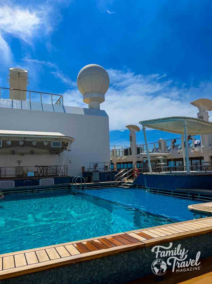 A swimming pool on the deck of a ship under a bright blue sky.